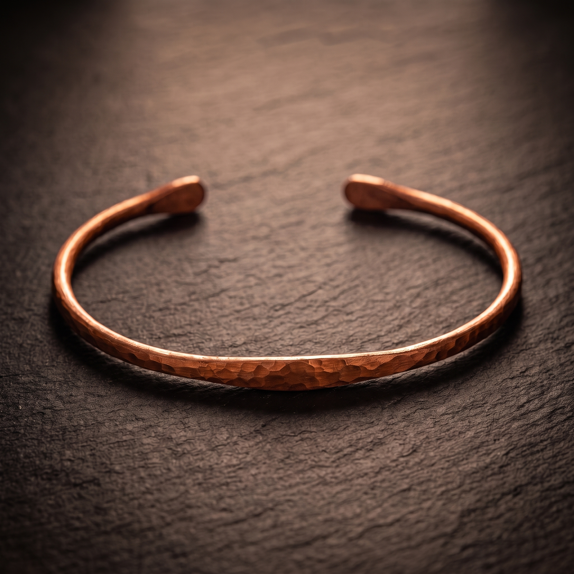 Hand-hammered copper bangle on dark slate